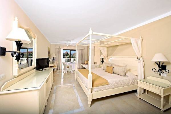 Hotelzimmer im Bahia Principe Luxury Ambar mit vierpfostenbett und Fernseher.