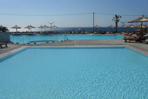 Zwei Swimmingpools am Akti Palace Hotel mit Blick auf das Meer und Liegestühlen.