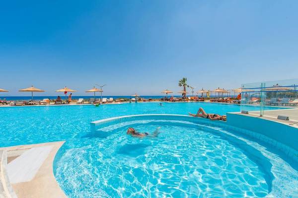 Akti Palace Swimming Pool mit Liegestühlen und Sonnenschirmen am Strand