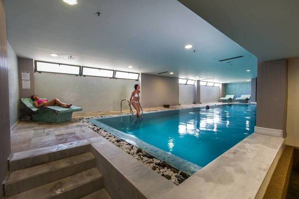 Ein mädchen steht im innenpool des akti-palastes und ein anderes mädchen liegt auf einer liege