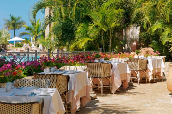 Außenbereich des Iberostar Grand El Mirador Hotels mit gedeckten Tischen und farbenfrohen Blumen.