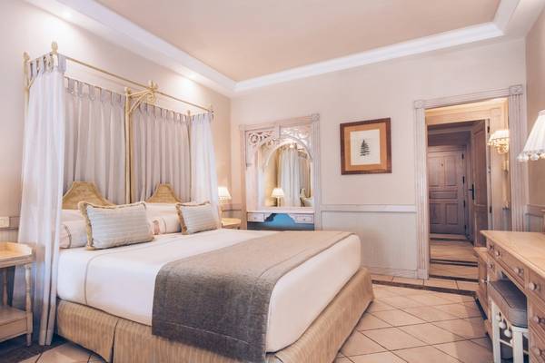 Schlafzimmer im Iberostar Grand El Mirador Hotel mit einem großen Bett, Baldachin und dekorativen Lampen.