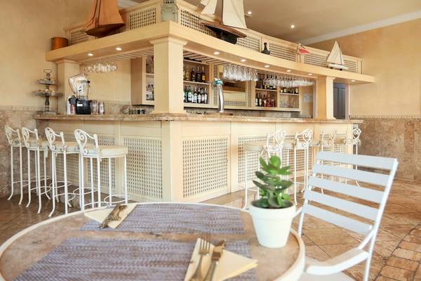 Die Bar im Iberostar Grand El Mirador Hotel mit weißer Theke, Stühlen und Flaschen.