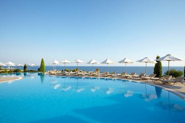 Poolbereich des Ikos Oceania Hotels mit Sonnenschirmen und Sonnenliegen am Meer