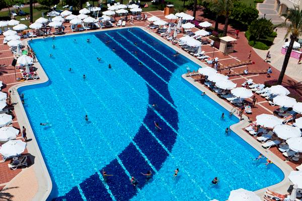 Luftaufnahme des großen Swimmingpools im Selectum Family Resort Side mit vielen Gästen, Sonnenschirmen und Liegestühlen.