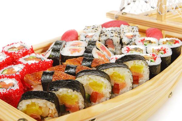 Verschiedene Sushi in einer hölzernen Bootsform präsentiert.