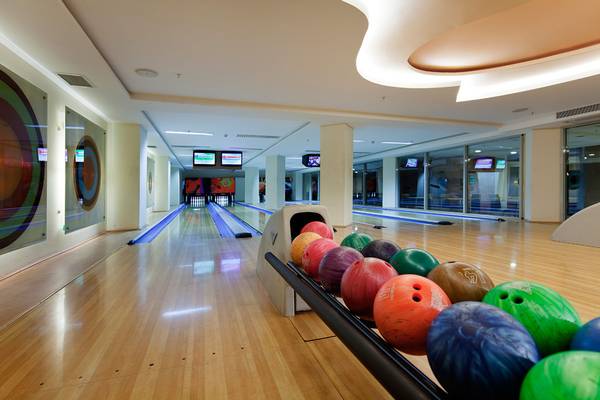 Bowlinghalle im Selectum Family Resort Side mit leeren Bahnen und Bowlingkugeln.