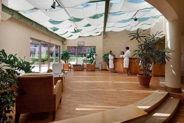 Empfangsbereich des Selectum Family Resort Side mit zwei Angestellten und Holzböden