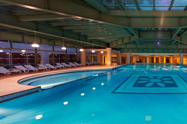 Innenpool des Selectum Family Resort Side mit weißen Sonnenliegen und Glasdach