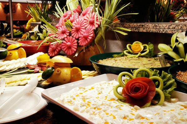 Buffet-Tisch mit verschiedenen Lebensmittel-Arrangements und Blumen-Dekorationen.