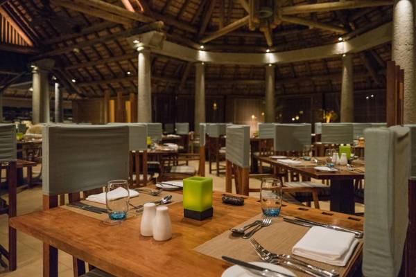Innenbereich des Sands Suites Resort & Spa mit gerundeten Tischen und Stühlen, Holzdekoration und sanfter Beleuchtung.