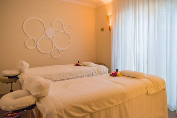 Massage-Behandlungsraum im Sands Suites Resort & Spa mit zwei Massageliegen und einem Wanddesign.