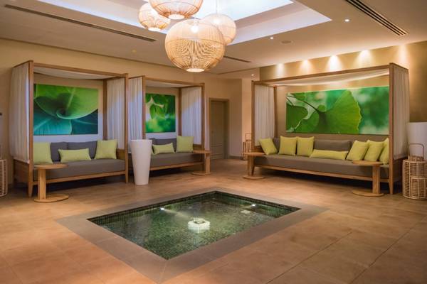 Loungebereich im Sands Suites Resort & Spa mit Sofas, Wasserbecken und grünen Pflanzenbildern.