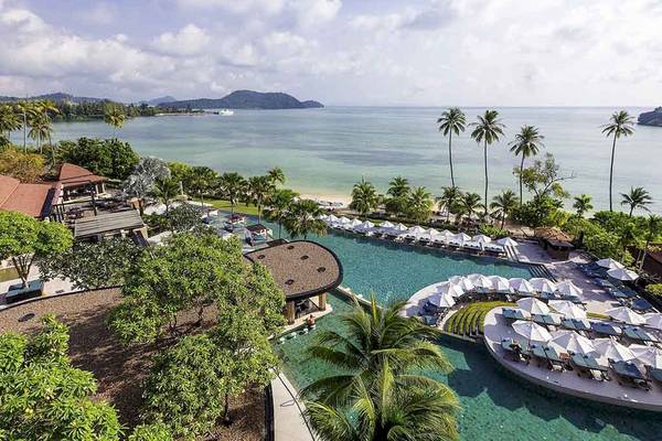 Aussicht auf das Pullman Phuket Panwa Beach Resort am Strand mit Pool und Sonnenschirmen.