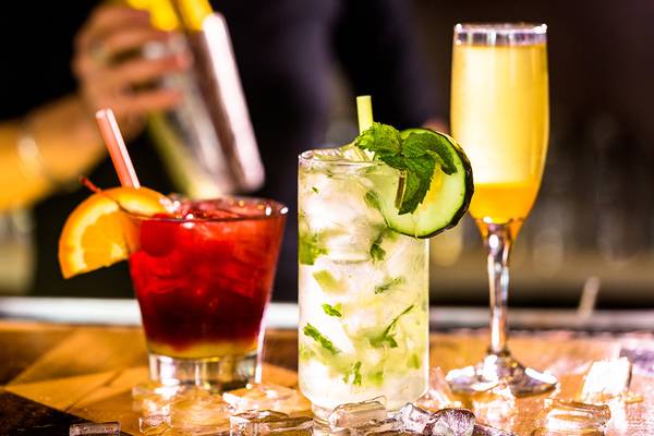 Cocktails auf der Bar mit Barkeeper, der einen Cocktail mixt.
