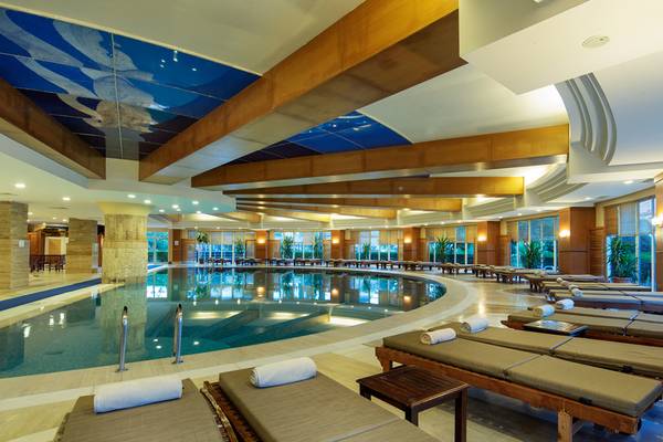 Innenpool des Crystal Admiral Resort Suites & Spa mit Liegen und einem bemalten Dach.