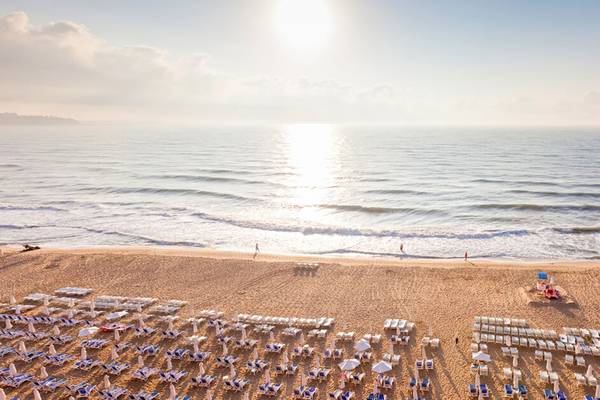 Strand des Sol Luna Bay All Inclusive Hotels mit Sonnenuntergang und vielen Sonnenliegen