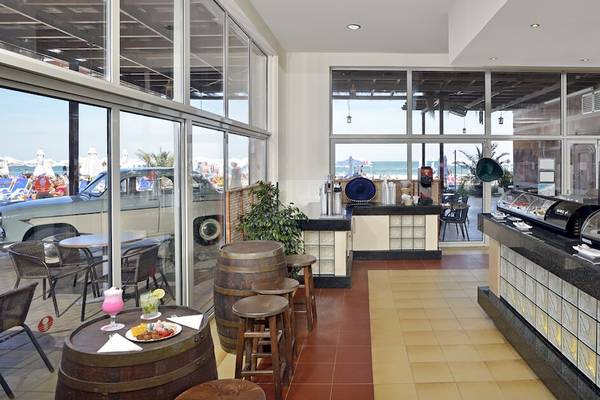 Innenansicht der Bar im Sol Luna Bay All Inclusive Hotel mit Tischen, Stühlen und Meeresblick.