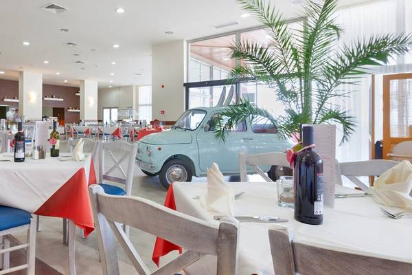 Restaurant im Sol Luna Bay All Inclusive Hotel mit Tisch und Stühlen, dekoriert mit roten und weißen Tischdecken.