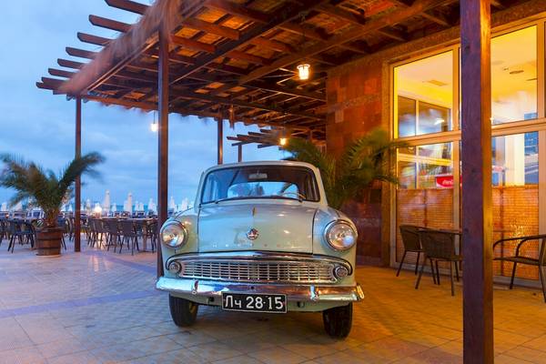 Ein altes Auto steht vor dem Sol Luna Bay All Inclusive Hotel am Abend.
