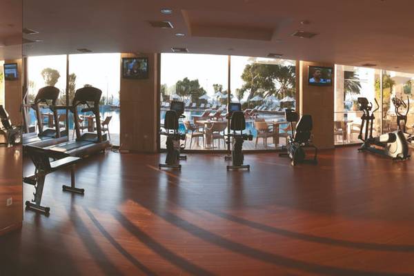 Fitnesscenter im Rhodes Bay Hotel & Spa mit Blick auf den Pool und Außenbereich