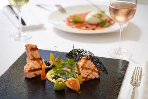 Feine Speisen auf einem Tisch im Rhodes Bay Hotel & Spa mit gebratenem Lachs, Gemüse und Getränken.