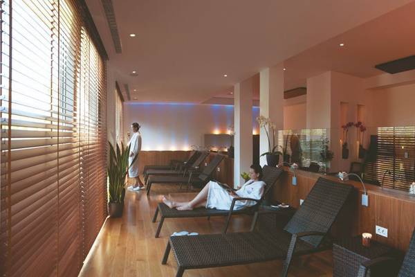 Spa-Lounge im Rhodes Bay Hotel & Spa mit zwei Frauen, eine liest ein Buch und die andere steht neben einer Pflanze.