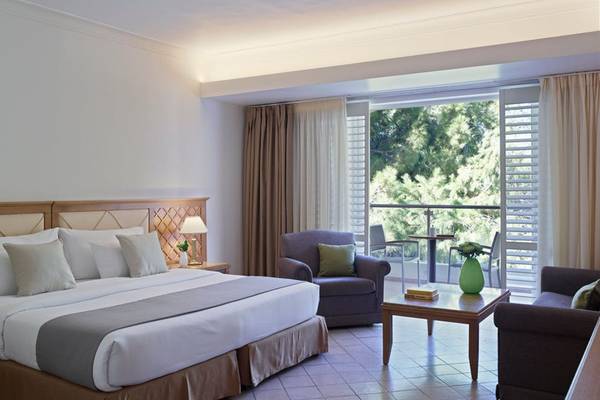 Zimmer im Rhodes Bay Hotel & Spa mit einem großen Bett, zwei Sesseln, einem Tisch und einem Balkon.