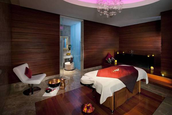 Spa-Behandlungsraum im Conrad Abu Dhabi Etihad Towers Hotel mit Massagetisch, Kerzen und Holzwänden.