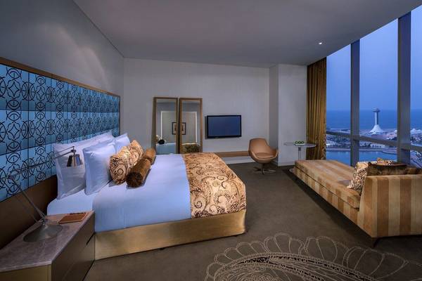 Innenansicht eines eleganten Zimmers im Conrad Abu Dhabi Etihad Towers mit großem Bett, Sofa und Meerblick.
