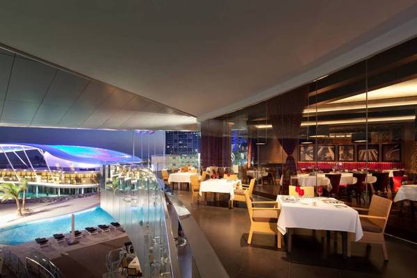 Aussicht auf das Conrad Abu Dhabi Etihad Towers Restaurant mit Tischen und Stühlen und einem Pool im Hintergrund.