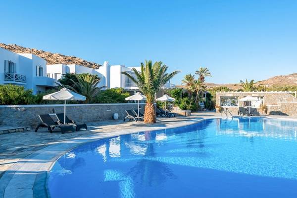 Außenpool des Sunrise Mykonos Hotels mit weißen Liegestühlen und Palmen.