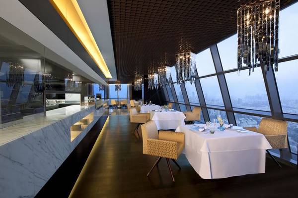 Innenansicht des Restaurants im Conrad Abu Dhabi Etihad Towers Hotel mit weißen Tischen und Stühlen.