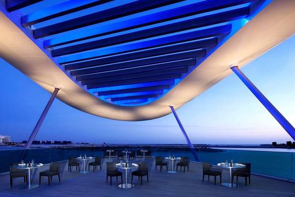 Außenterrasse des Conrad Abu Dhabi Etihad Towers mit blauen Beleuchtung und Tischen
