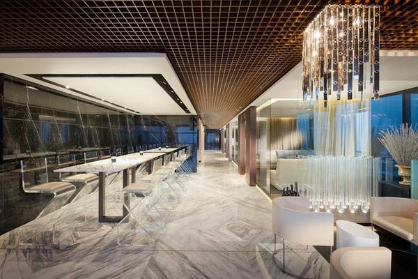 Innenbereich des Conrad Abu Dhabi Etihad Towers mit weißen Möbeln, Marmorboden und einer großen Deckenleuchte.