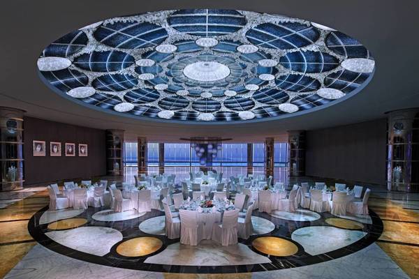 Bankettsaal im Conrad Abu Dhabi Etihad Towers mit runden Tischen und einer beeindruckenden Deckenleuchte.