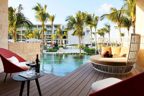 Außenbereich des TRS Coral Hotels mit Pool, Loungemöbeln und Palmen