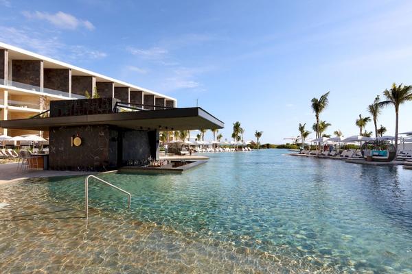 Außenbereich des TRS Coral Hotels mit einem großen Pool und Sonnenliegen.