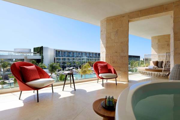 Balkonbereich des TRS Coral Hotels mit zwei roten Sesseln, einer Badewanne und Blick auf das Meer.