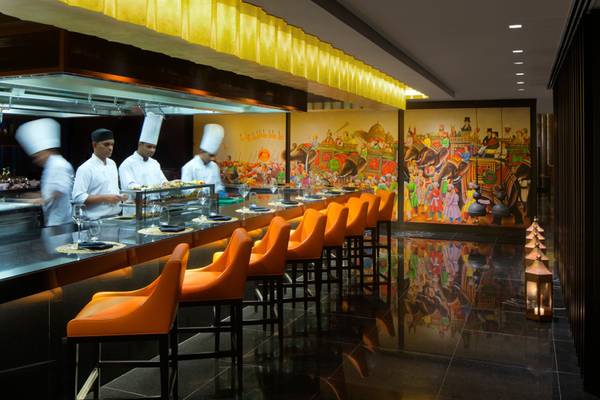 Innenbereich des Restaurants im Taj Dubai Hotel mit Küchenpersonal und kunstvollen Wandgemälden.