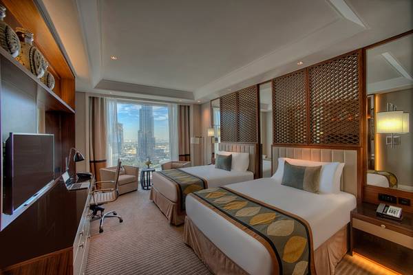 Hotelzimmer im Taj Dubai mit zwei Betten, Schreibtisch, Fernseher und Stadtblick.
