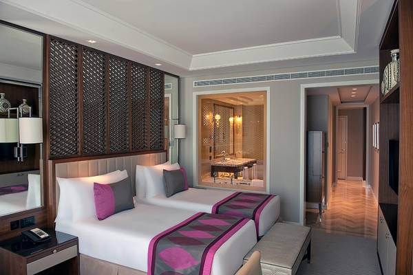 Innenansicht eines Doppelzimmers im Taj Dubai mit zwei Betten, Dekor und Badezimmer.