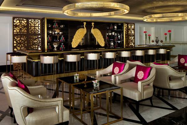Innenansicht der Bar im Taj Dubai Hotel mit goldenen Pfauen-Design, eleganten Stühlen und Theken.