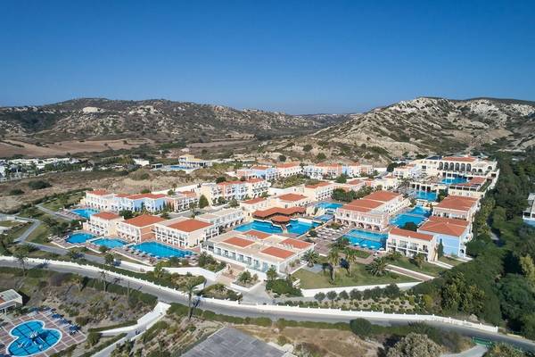 Luftaufnahme des Porto Bello Royal Hotels mit mehreren Swimmingpools und Bergpanorama im Hintergrund.