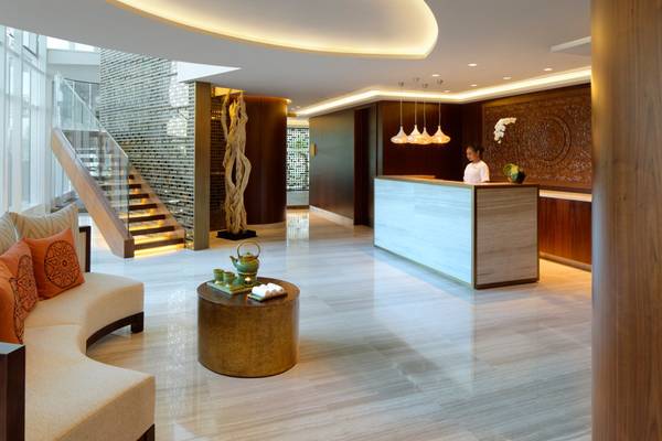 Empfangsbereich im Taj Dubai Hotel mit Rezeptionstresen, Couch, Tisch und Treppen