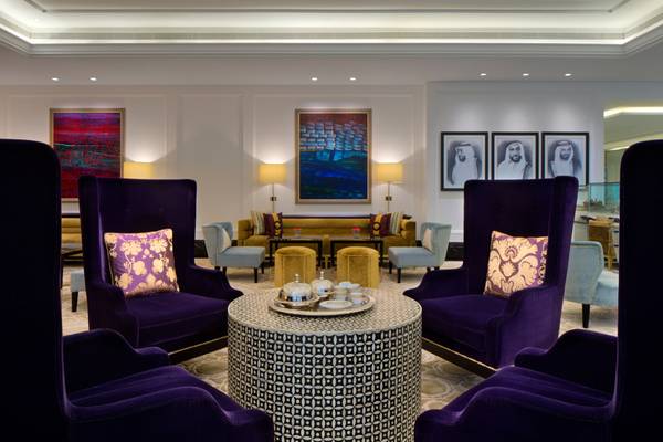 Loungebereich im Taj Dubai Hotel mit violetten Sesseln, einem runden Tisch und dekorativen Gemälden.