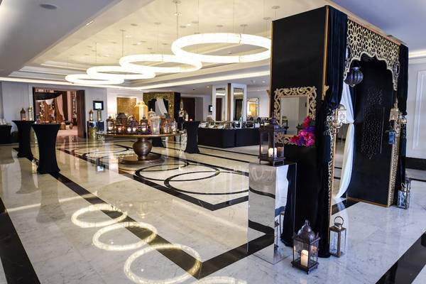 Foyer des Taj Dubai Hotels mit schwarzen und weißen Marmorboden, schwarzen Vorhängen und goldenen Kronleuchtern.