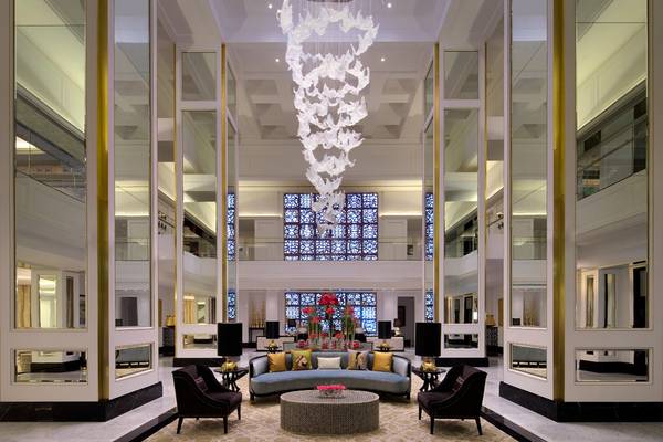 Foyer des Taj Dubai Hotels mit Kristallleuchte und Blumenarrangement.