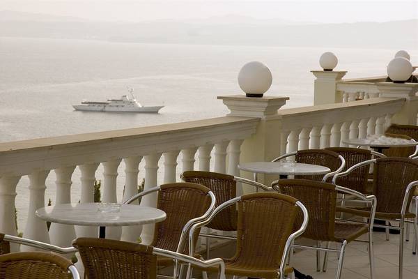 Terrasse mit Blick auf das Meer im Sunshine Corfu Hotel & Spa mit Tischen und Stühlen.
