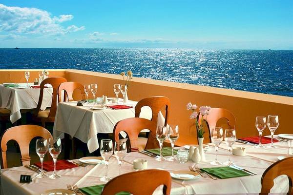 Restaurant mit Meerblick im Sunshine Corfu Hotel & Spa mit gedeckten Tischen und Blick auf das offene Meer.